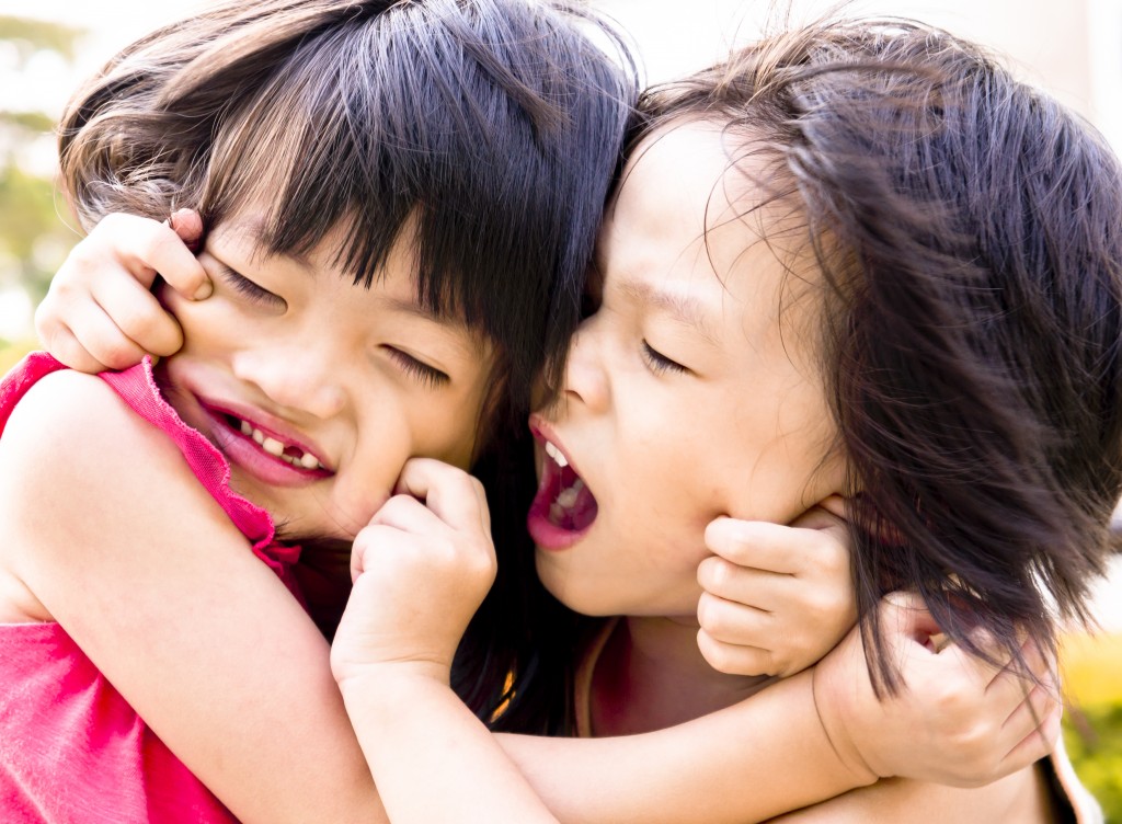 Sibling, brother and sister fighting pulling each other faces