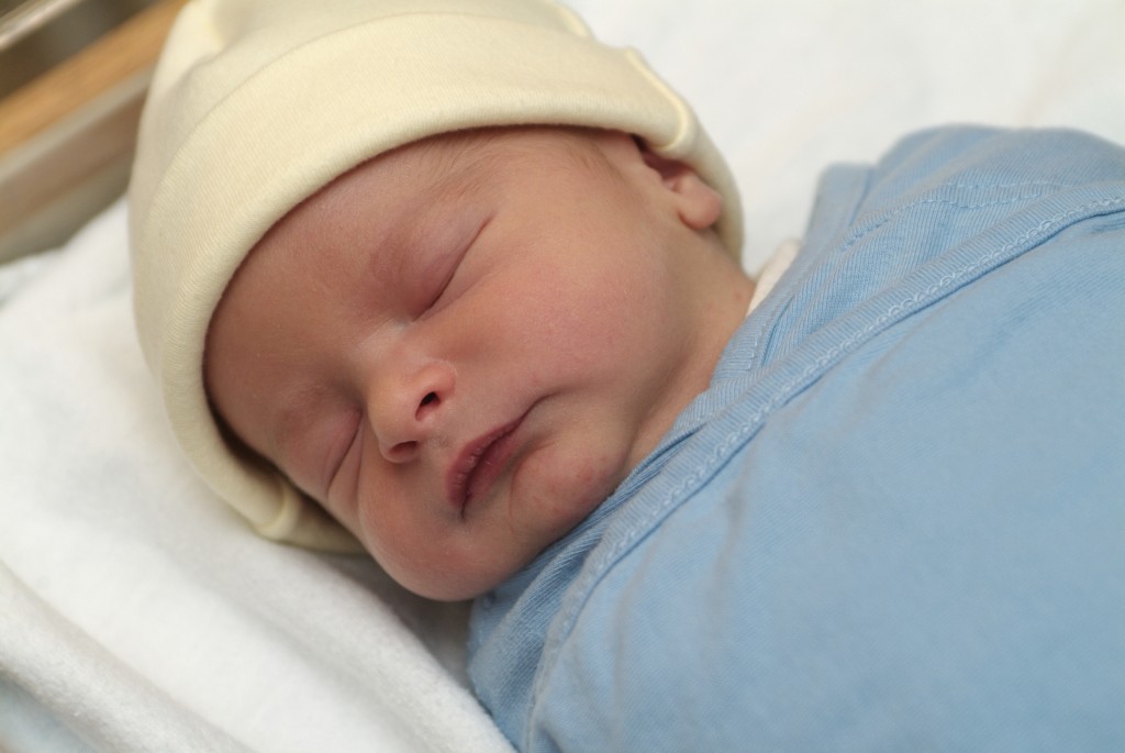 A swaddled newborn baby is sleeping.