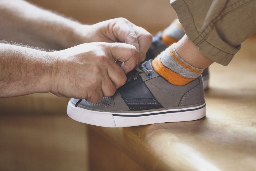Father helping to tie his son's shoes